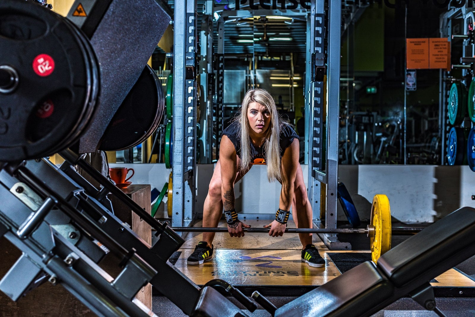 Female weightlifter in gym lifting bar bells